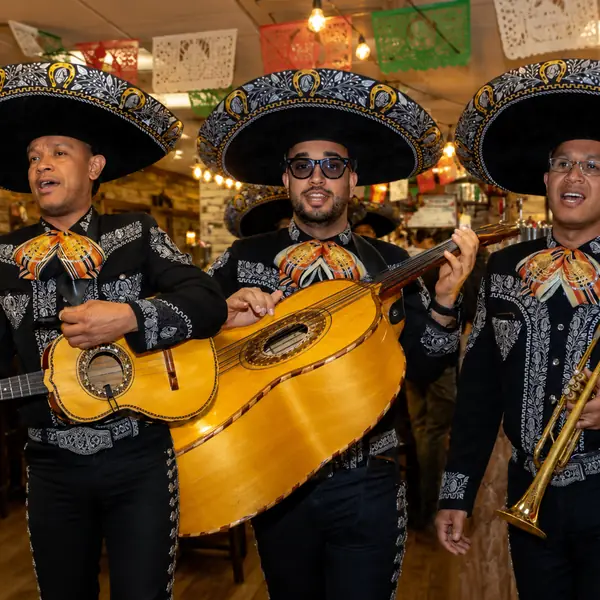 Trío de mariachi en Madrid con traje negro tocando en un restaurante